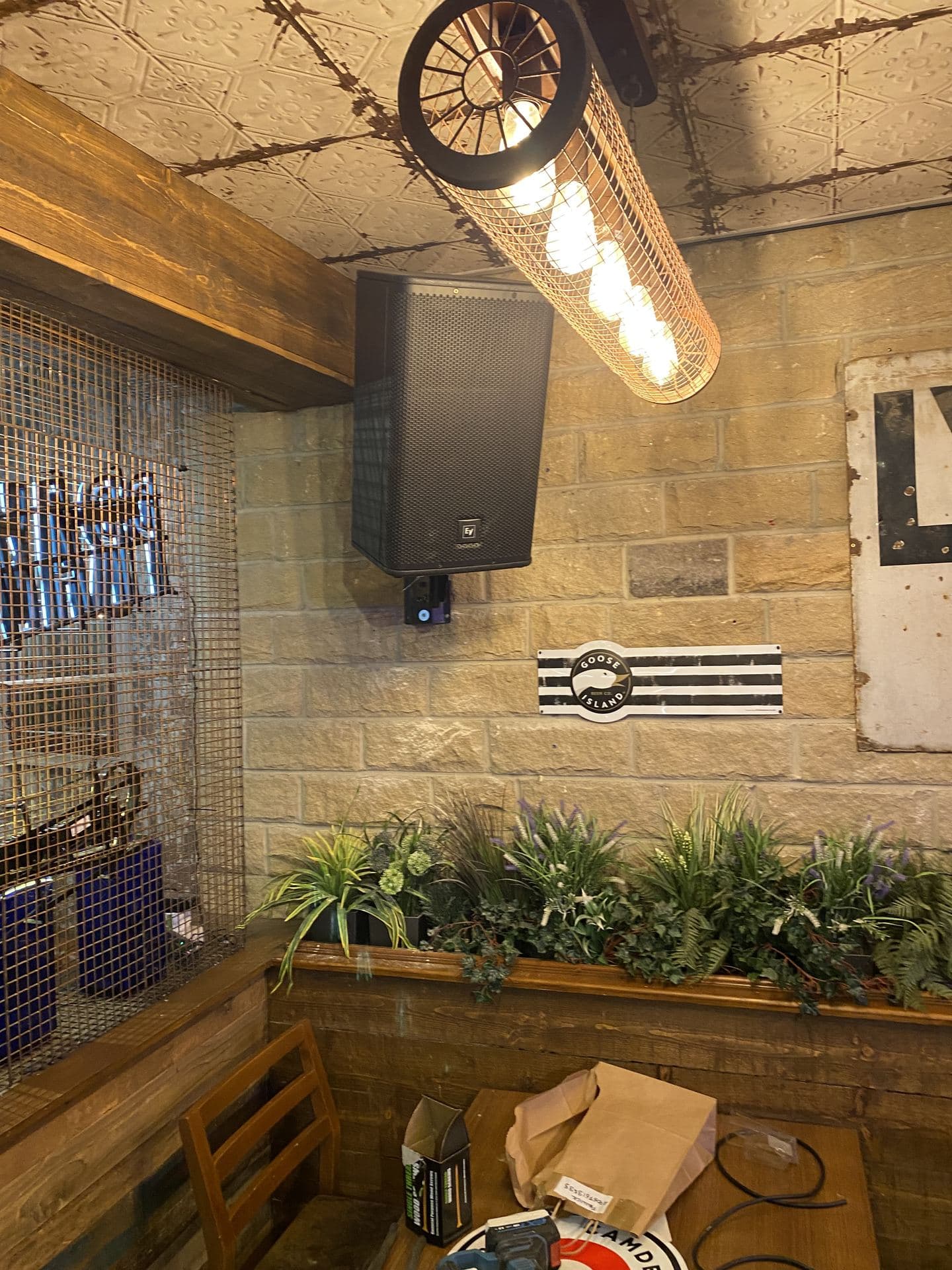 Wall-mounted commercial speaker beside a feature light fitting