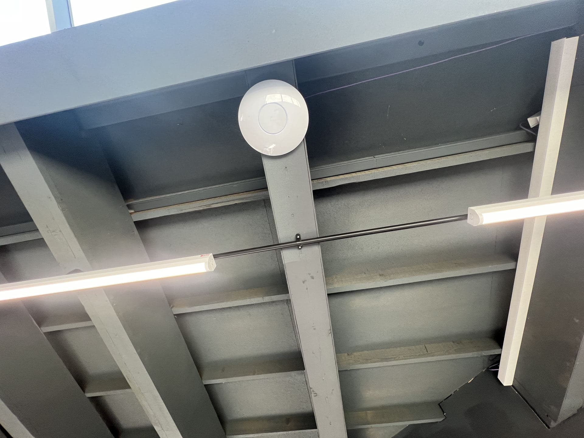 UniFi access point mounted on a warehouse ceiling beam